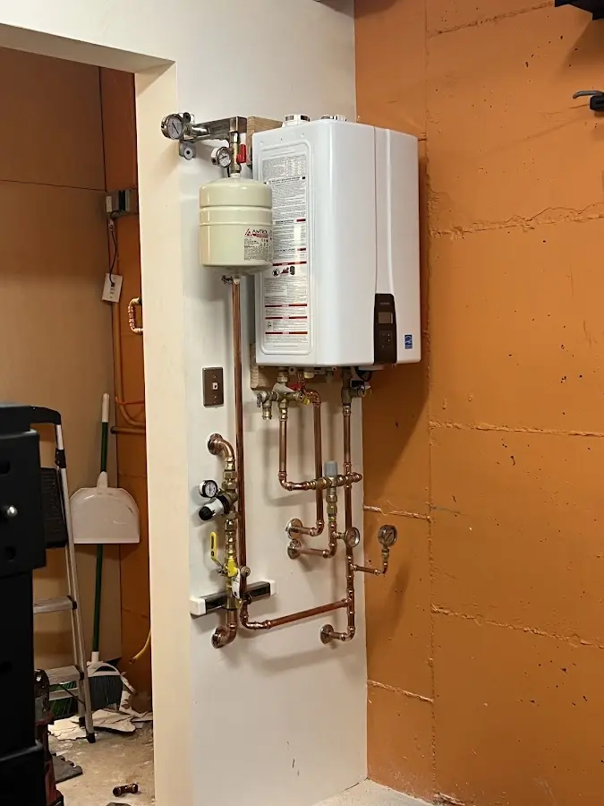 Plumbing technician inspecting water heater connections in East Petersburg